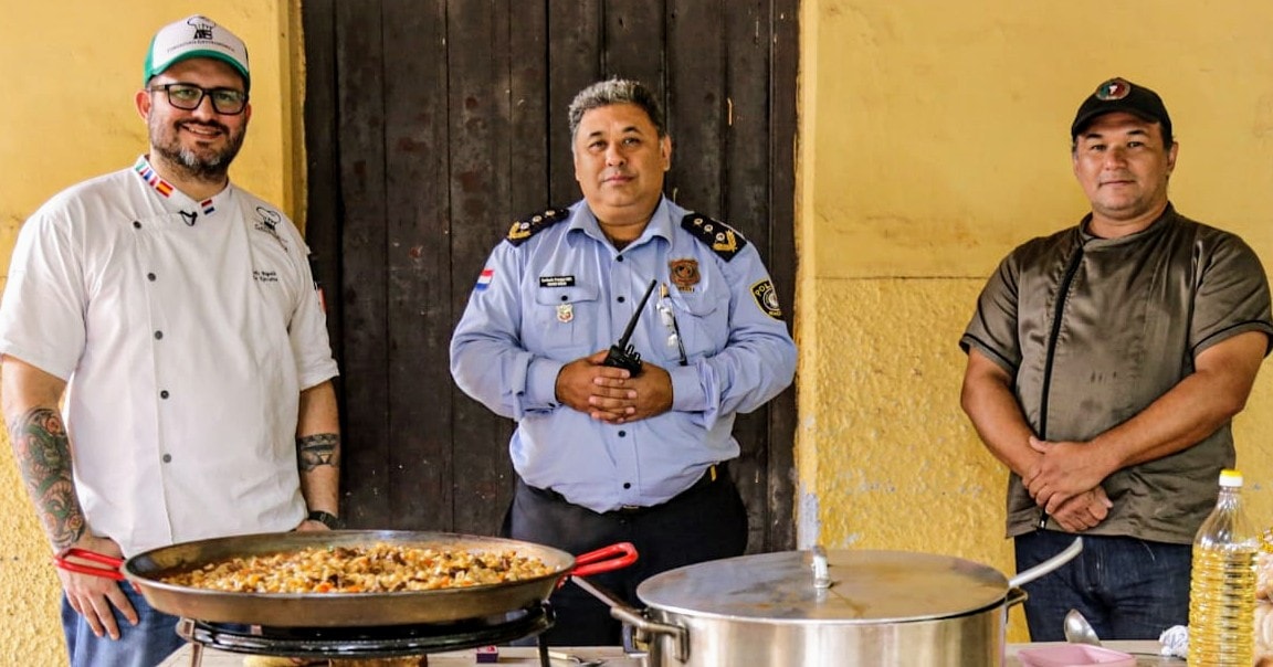 Chefs junto a policía posando para la fotografía frente a sus ollas