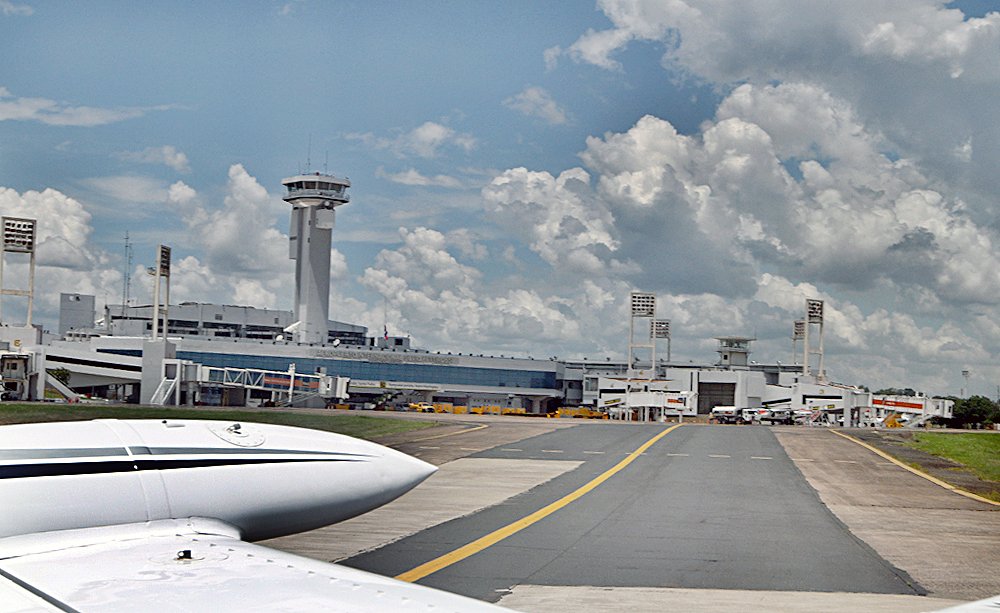 Vista de la pista de aterrizaje, con el aeropuerto Silvio Pettirossi de fondo, y se puede ver parte del ala de un avión.