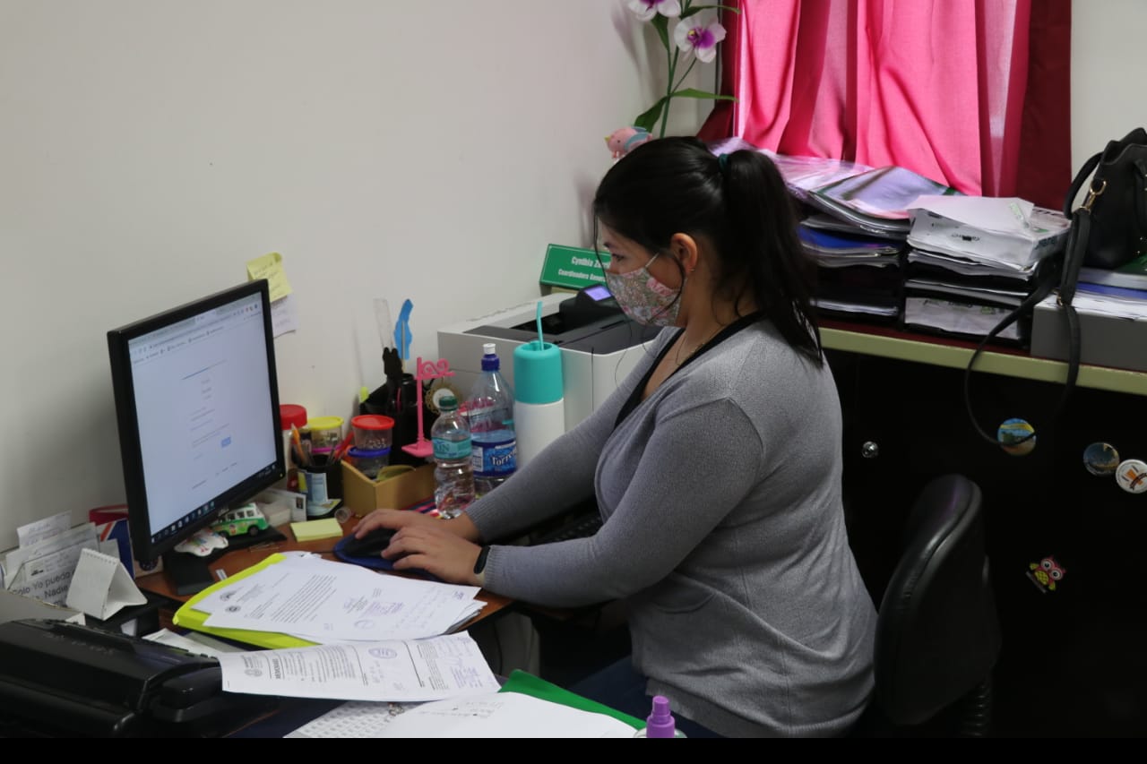 Mujer sentada frente a la computadora manteniendo una buena postura.