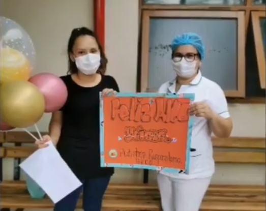 Paciente y médica posando con globos y un cartel, celebrando el alta