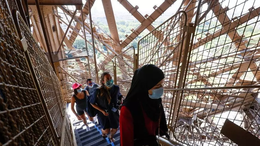 Visitantes con mascarilla suben por las escaleras del monumento, en el día de su reapertura parcial. Foto: AFP