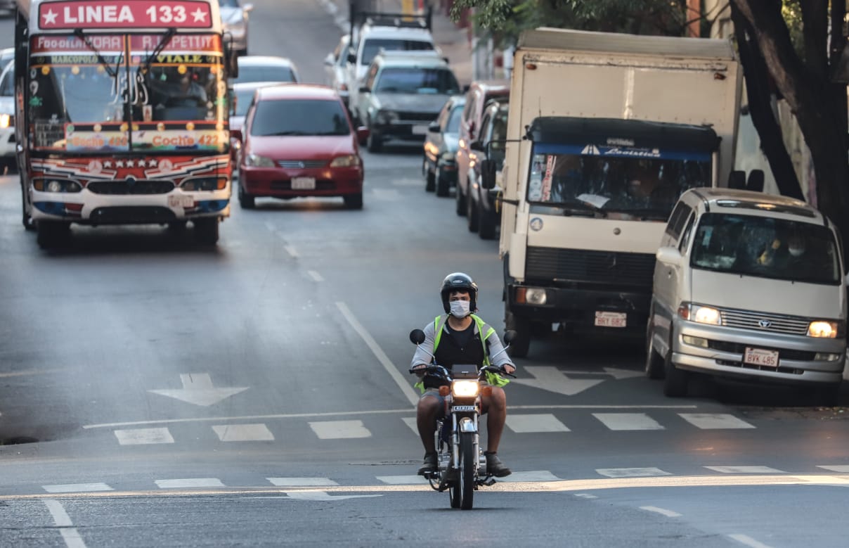 Calles de Asunción, pasa una moto con un hombre vistiendo el tapabocas y casco.