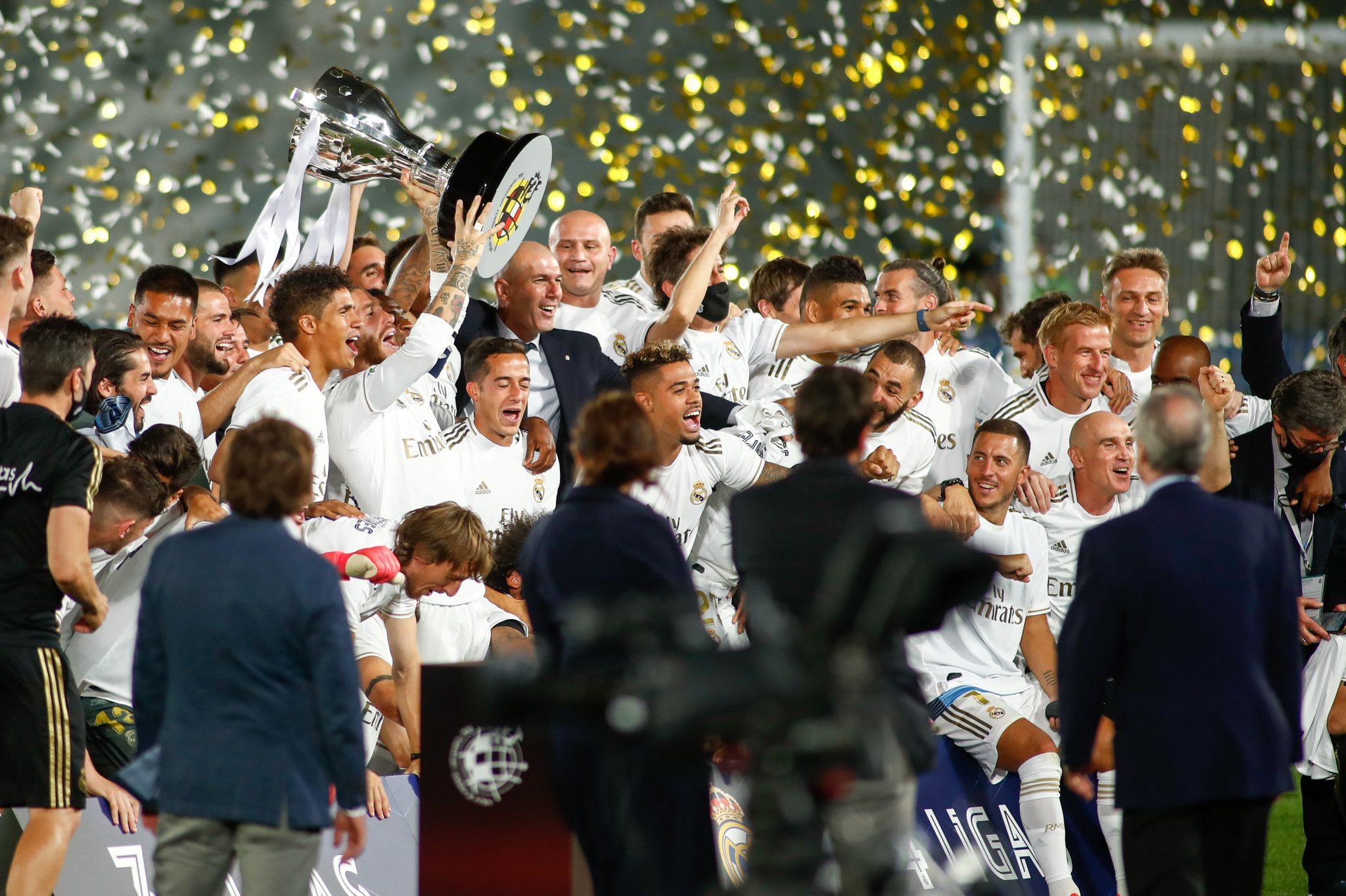 Equipo del Real Madrid festejando el campeonato con la copa y confetti cayendo desde arriba.