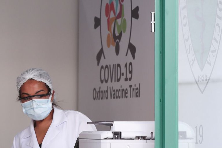 Trabajadora de laboratorio frente a un cartel de pruebas para la vacuna de Oxford contra Covid-19.