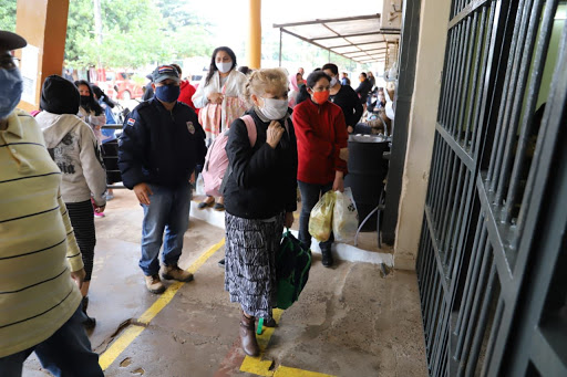 Visitantes esperando en fila para ingresar al penal de tacumbú, utilizando tapabocas y cumpliendo con el distanciamiento físico.