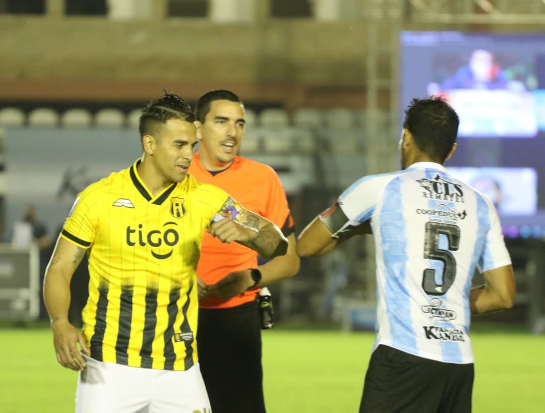 Jugador de guaraní (de frente) saludando con el codo a jugador del guaireña (de espaldas).