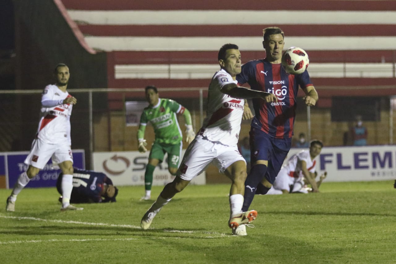 Jugador de Cerro Porteño busca la pelota en el aire, le sigue un jugador de River Plate.
