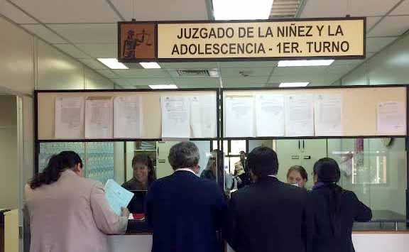 Ventanilla del juzgado de la niñez y adolescencia-1er turno, con personas haciendo gestiones y esperando en la fila.