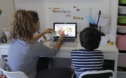 Foto ilustrativa de un adulto enseñando a un niño con una computadora.