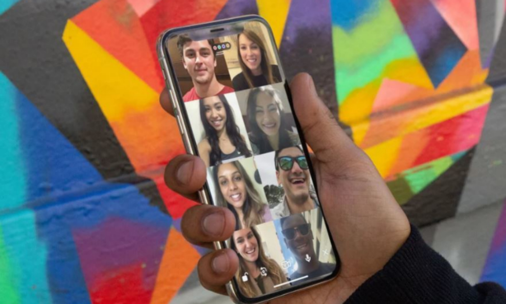 Imagen ilustrativa de una mano sosteniendo un teléfono con la pantalla dividida en 8 con una persona en cada porción. Representa las reuniones sociales virtuales.