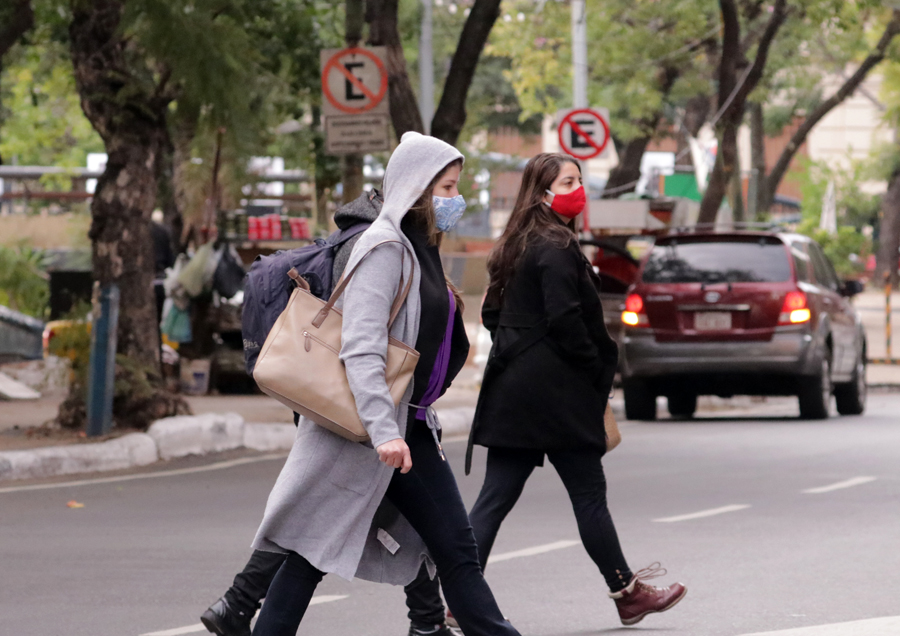Personas abrigadas utilizando tapabocas cruzando las calles.