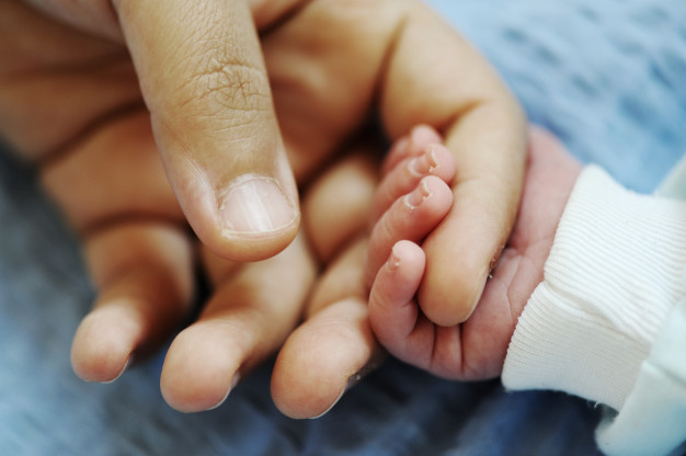 Imagen ilustrativa. Mano de un recién nacido agarrando la mano de un adulto.