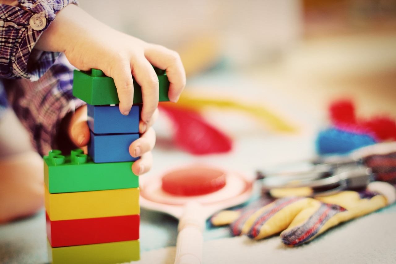 Imagen ilustrativa. Manos de un niño jugando con bloques de juguete.