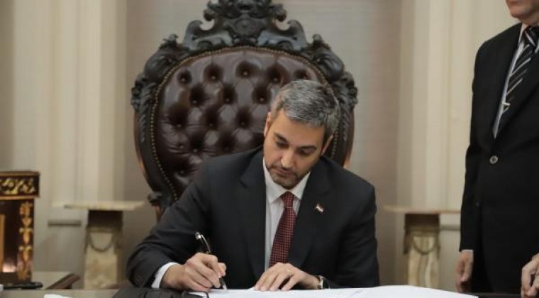 Presidente Mario Abdo Benítez firmando un documento en su despacho.