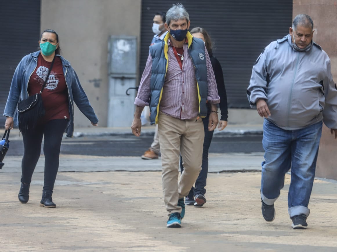 Personas caminando en las calles usando tapabocas.