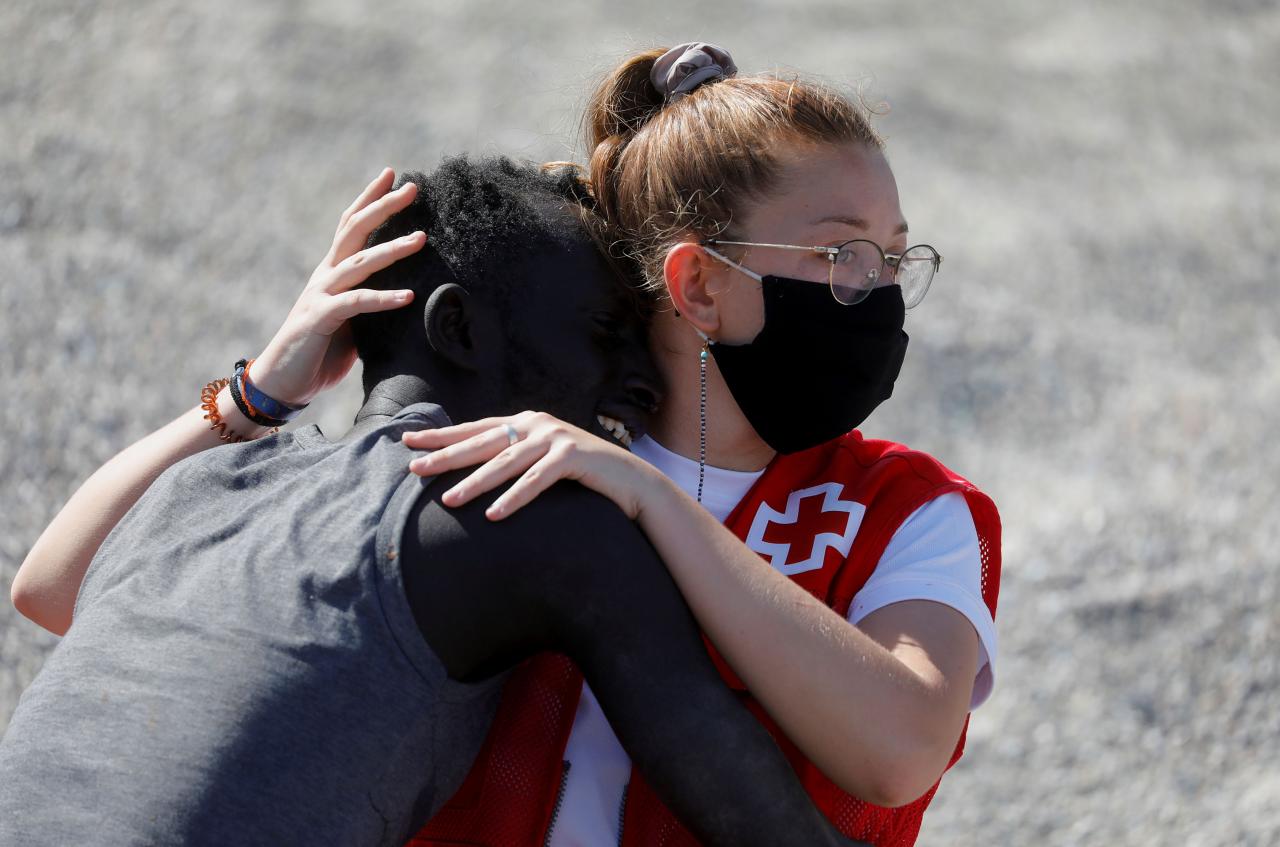 Un miembro de la Cruz Roja ayuda a un ciudadano marroquí en la playa de El Tarajal. Foto: Reuters.